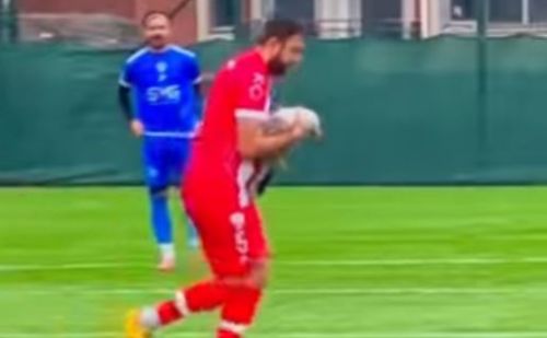 Footballeur en maillot rouge sur la pelouse, portant une mouette dans 
